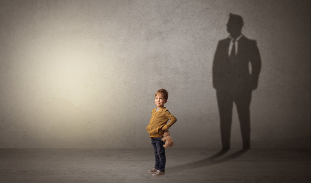 Little boy imagine that he will be businessman and illustrating his future in a big shadow
