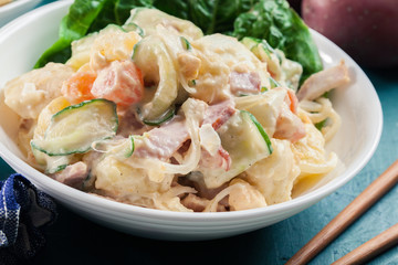 Delicious potato salad with ham, egg and cucumber