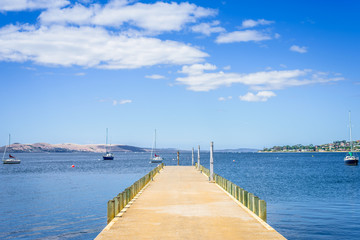 Fototapeta na wymiar Pretty view to stunning blue water of southern ocean antarctica on warm sunny day with blue sky mountains and some fishing boats yacht cruising capital city, Hobart, Tasmania, Australia - 11-17-20:
