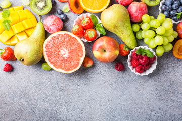 Fresh assorted fruits and berries on light gray background. Colorful clean and healthy eating. Detox food. Copy space. Top view.