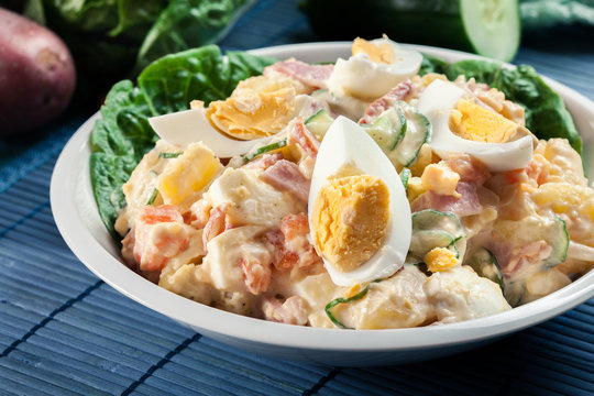 Delicious potato salad with ham, egg and cucumber