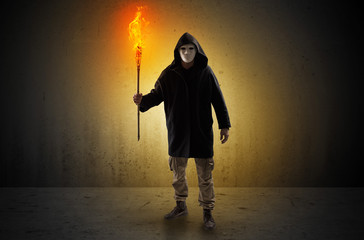 Ugly scary man with burning flambeau walking in an empty space