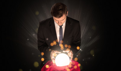 Fototapeta premium Gorgeous businessman sitting with sparkling magic ball in his lap 
