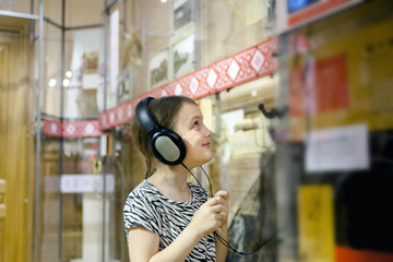   girl in   museum  near  exhibit with headphones.