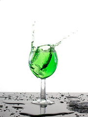 Cold tarkhun in a glass, splash and ice, spilled water