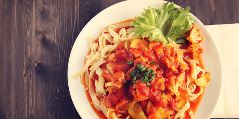 Ribbon pasta with Arrabiata sauce. Close up. Mediterranean dish. Tagliolini pasta with vegetables. Cauliflower, courgette and tomato stew. Italian cuisine. Vegan and vegetarian. Top view. Copy space.