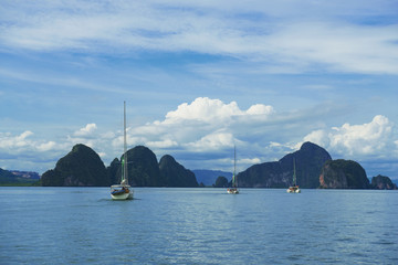 Three boats sailing through tropical group of islands with limestone caves inside in Ao Phang-Nga National Park, Andaman Sea, Thailand. November 12, 2017