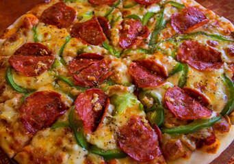 Pizza with green pepper and pepperoni sausage. Italian pizza closeup. Whole pizza with pepperoni.