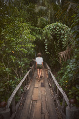 Traveling girl on the wooden bridge. Pretty young woman in the jungle. Summer lifestyle and adventure photo