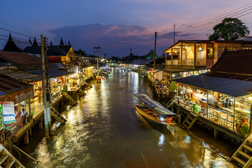 Samut Songkhram / Thailand - April 21 2018: Twilight view Amphawa market canal and Many People as tourists walking, shopping, the most famous of floating market of Thailand.