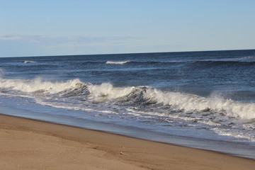 Waves crashing on isolated empty sandy coastal ocean beach 