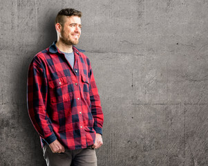 Young handsome man confident and happy with a big natural smile looking side