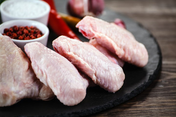 Raw chicken wings on black stone on wooden background