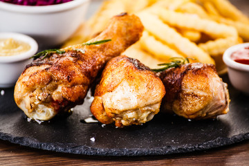 Roast chicken drumsticks with chips and vegetables
