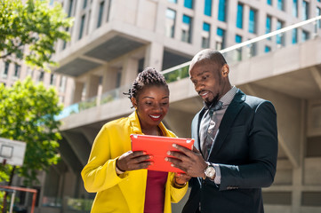 Man and woman smile with tablet outdoors