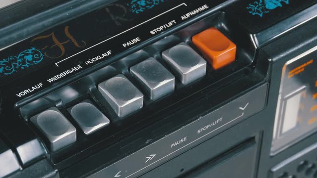 Pushing Button on a Tape Recorder, Play, Stop, Rec, ff, Rew. Close-up. Man finger presses playback control buttons on vintage audio cassette player. Inscriptions in German