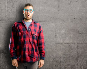 Young handsome man happy and surprised cheering expressing wow gesture