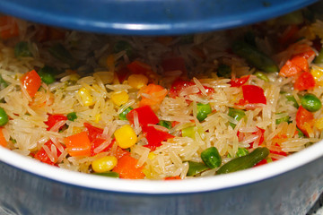Rise with fresh vegetables in blue saucepan. Asian healthy foog. Risotto background texture. Vegetarian tasty dinner