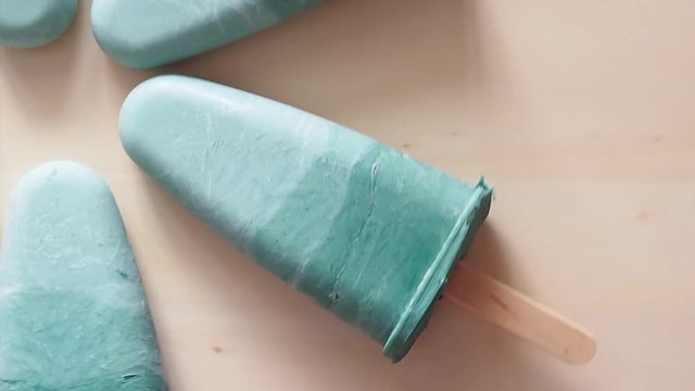 Superfood spirulina popsicles rotate on wooden tray. Ideas and recipes for healthy breakfast, summer vegetarian snack or vegan dessert. Popsicle with spirulina powder and coconut milk.