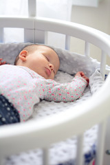 Newborn baby at home. New born child in wooden co-sleeper crib. Infant sleeping in bedside...