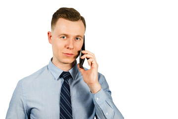 Portrait of young businessman dressed in blue shirt and tie talking on the mobile phone, isolated on white background