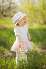 A child in a white hat in spring blooming gardens, with a flowering branch