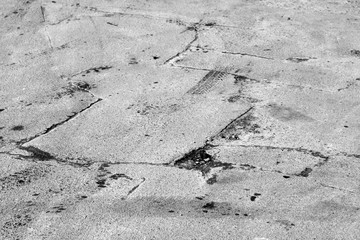 Damaged asphalt road in black and white.