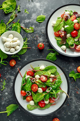 Fresh Cherry Tomato, Mozzarella salad with green lettuce mix and red onion. served on plate....