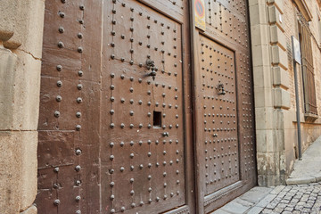 Closeup of beautiful old wood door with rusty handle and circular ornaments in Toledo