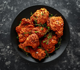 Fried crispy chicken legs, Thigh in a black plate with herbs.