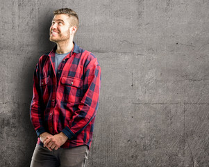 Young handsome man confident and happy with a big natural smile laughing looking up