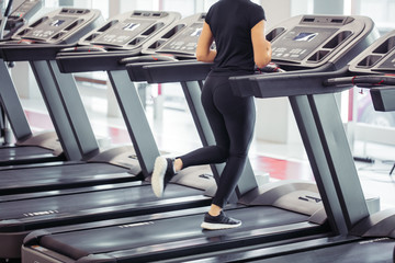 Fototapeta na wymiar Young focused fit woman running on treadmill