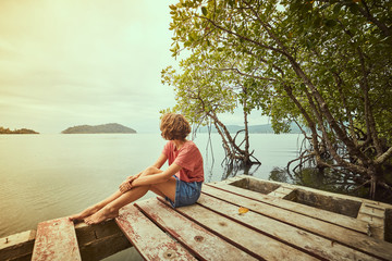 Traveling girl on the wood pier. Pretty young woman and tropical landscape. Summer lifestyle and...