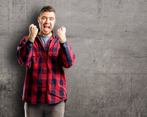 Young handsome man happy and excited expressing winning gesture. Successful and celebrating victory, triumphant