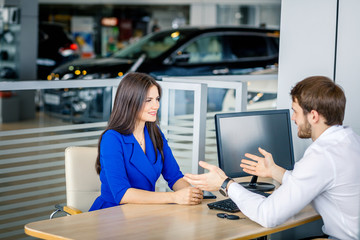 A ambitious sales agent prompting the young woman to byu a car she likes