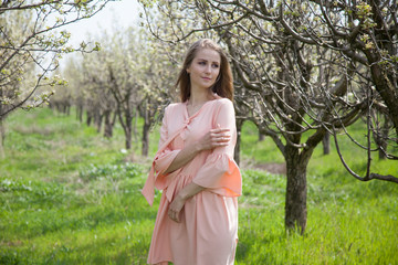 girl in peach dress walks by a blooming garden