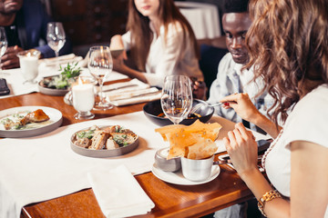 Cropped view of eating young people in restaurant, snacks and delicious food at focus