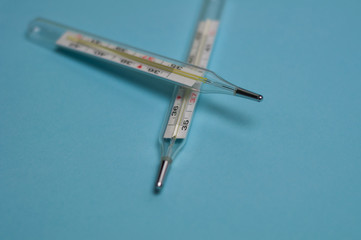 Two glass mercury thermometers on blue background