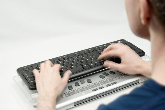 Blurred man in the foreground typing on keyboard, hands are on the move and an empty background