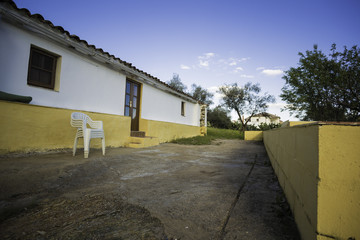 Antigua casa de campo con fachada blancas y sillas de plástico