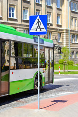 Passenger bus drives past the sign crosswalk on Central cobblestone paved road in Bialystok, Poland. Comfortable urban public transport and developed road infrastructure in Eastern Europe