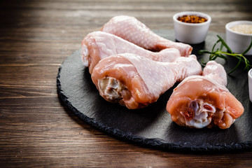 Raw chicken drumsticks on wooden background