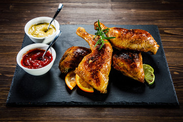 Roast chicken legs on black stone plate