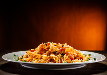 Pasta with tomato sauce and vegetables on wooden table