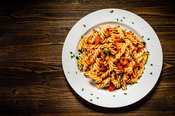Pasta with tomato sauce and vegetables on wooden table
