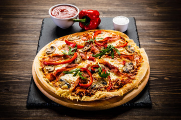 Pizza with ham and vegetables on wooden table