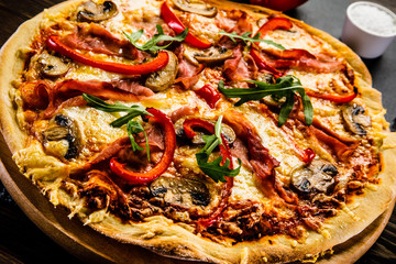 Pizza with ham and vegetables on wooden table