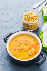 Healing comfort food, split pea soup in a pot on blue concrete background. Top view, copy space.