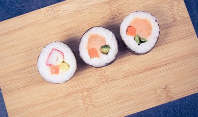 Various kinds of sushi on the wooden background.