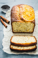 Cinnamon poppy seeds orange cake on light blue concrete background. Selective focus, space for text. 